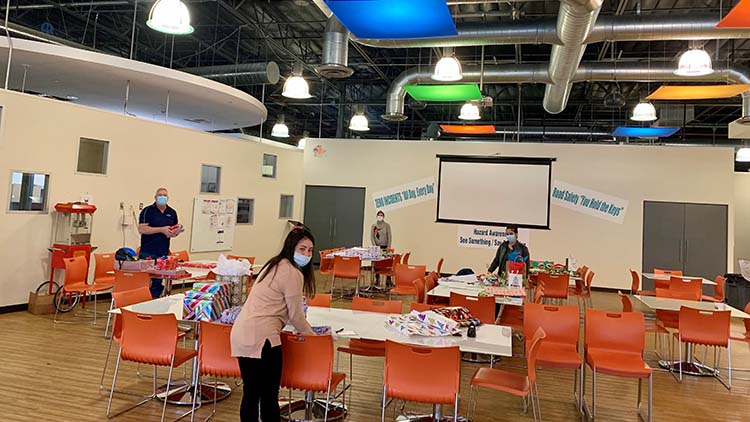 Pasonites wrapping gifts for the family they adopted for the holidays, socially distanced with masks on.